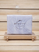 Marble-patterned lavender soap bar with 'Beauty by Francesca' branding on a wooden stand.