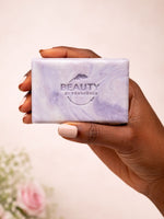 Hand holding a 'Beauty by Francesca' lavender soap bar against a light background