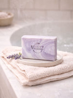 Purple marbled lavender  soap on a white plate with a towel and lavender flower in a bathroom setting