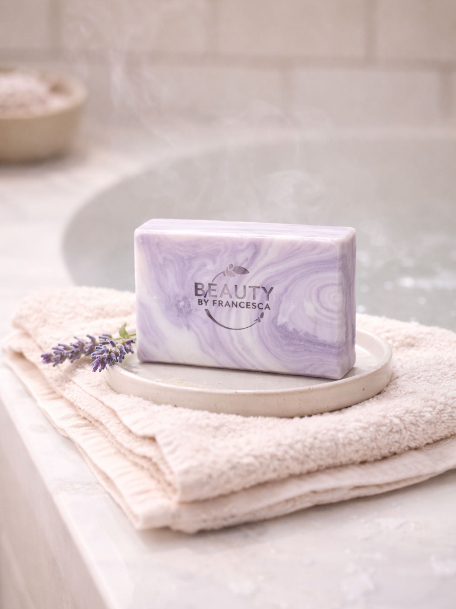 Purple marbled lavender  soap on a white plate with a towel and lavender flower in a bathroom setting