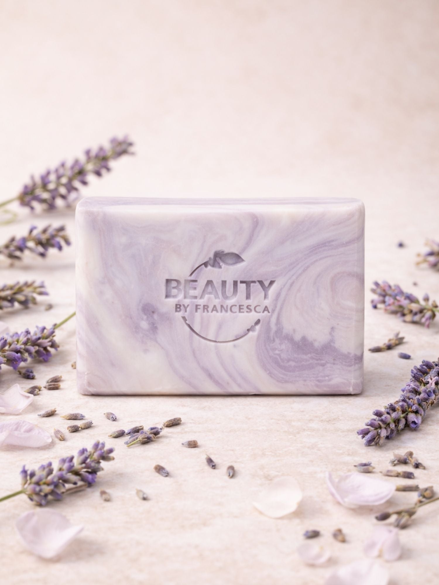 Marble-patterned lavender  soap bar with 'Beauty by Francesca' branding surrounded by lavender flowers on a light background.