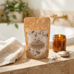 Luscious Lavender Bath Salts, 6 oz,  on the edge of a bathtub with a spa towel, a lit candle and small decorative bowl of salt and lavender buds