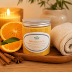 orange spice body scrub in spa setting with a towel and surrounded by oranges, cinnamon, and anise star