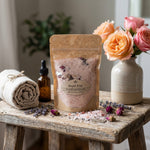 Royal Rose Bath Salt, 6 oz,  on a wood bench with fresh roses, a linen towel, and a small mound of pink salt