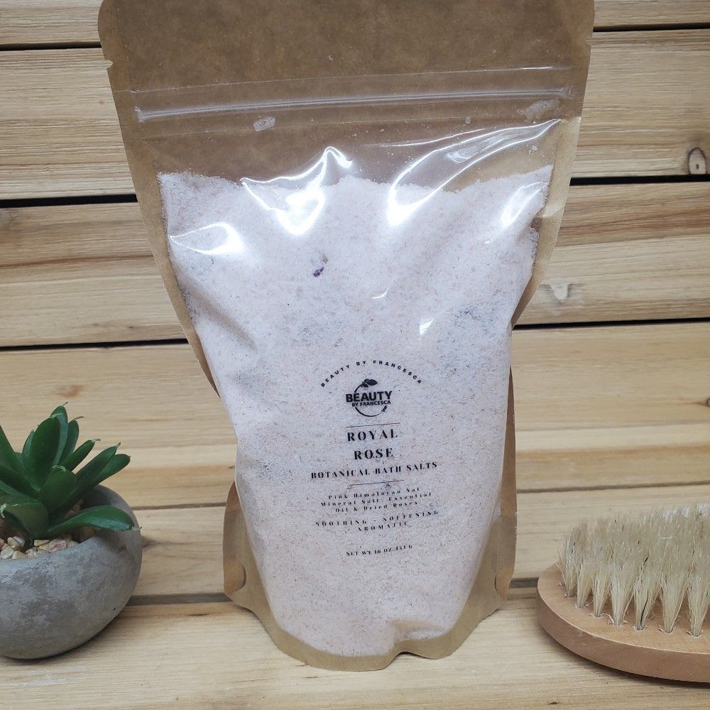 Bag of Royal Rose bath salts with a plant and brush on a wooden surface