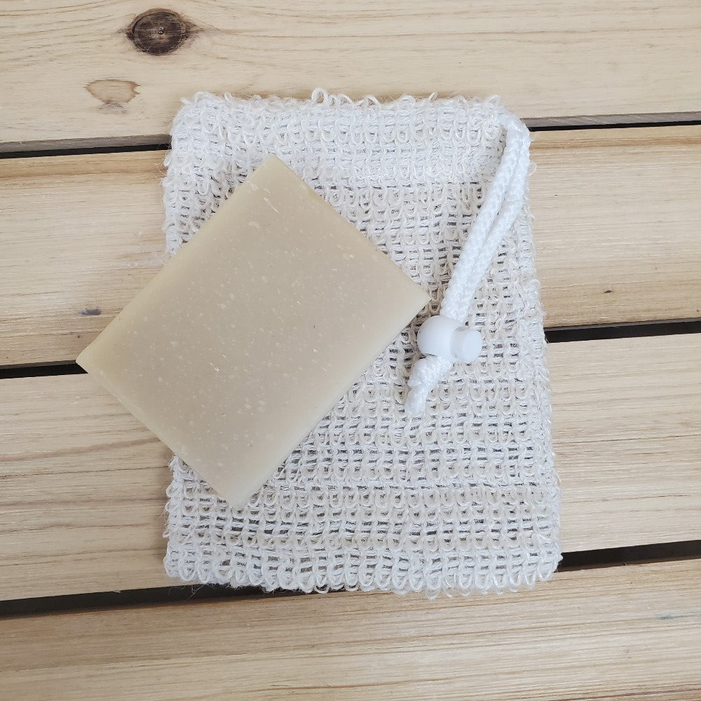 Bar of soap angled on top of a sisal soap saver  against a wooden background