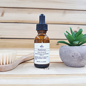 radiance facial oil next to plant and  facial brush wood  background