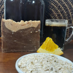 Handmade Natural Beer Soap Bar - Chocolate Oatmeal Stout next to orange wedge and oats
