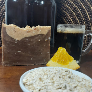 Handmade Natural Beer Soap Bar - Chocolate Oatmeal Stout next to orange wedge and oats