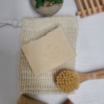 Coco shea coconut oil soap bar displayed with reusable soap bag and small scrub brush